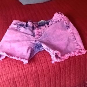 Jeans shorts that are pink have feathers on the bottom.
